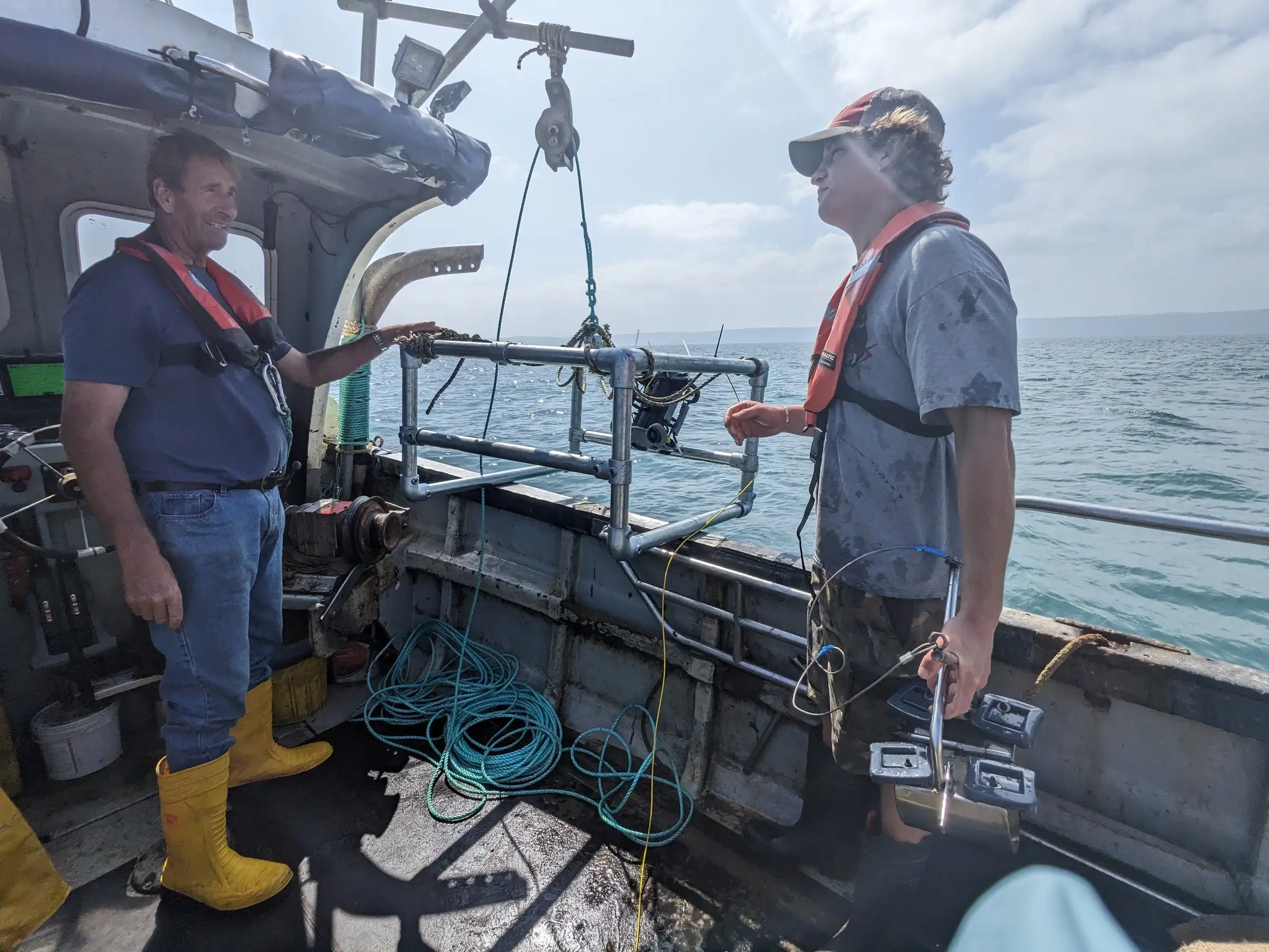 Two people on a boat deploying marine monitoring equipment