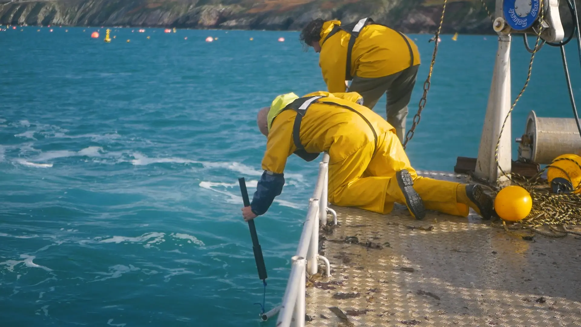 Crew in yellow oilskins lowering a GrowProbe over the side of a workboat