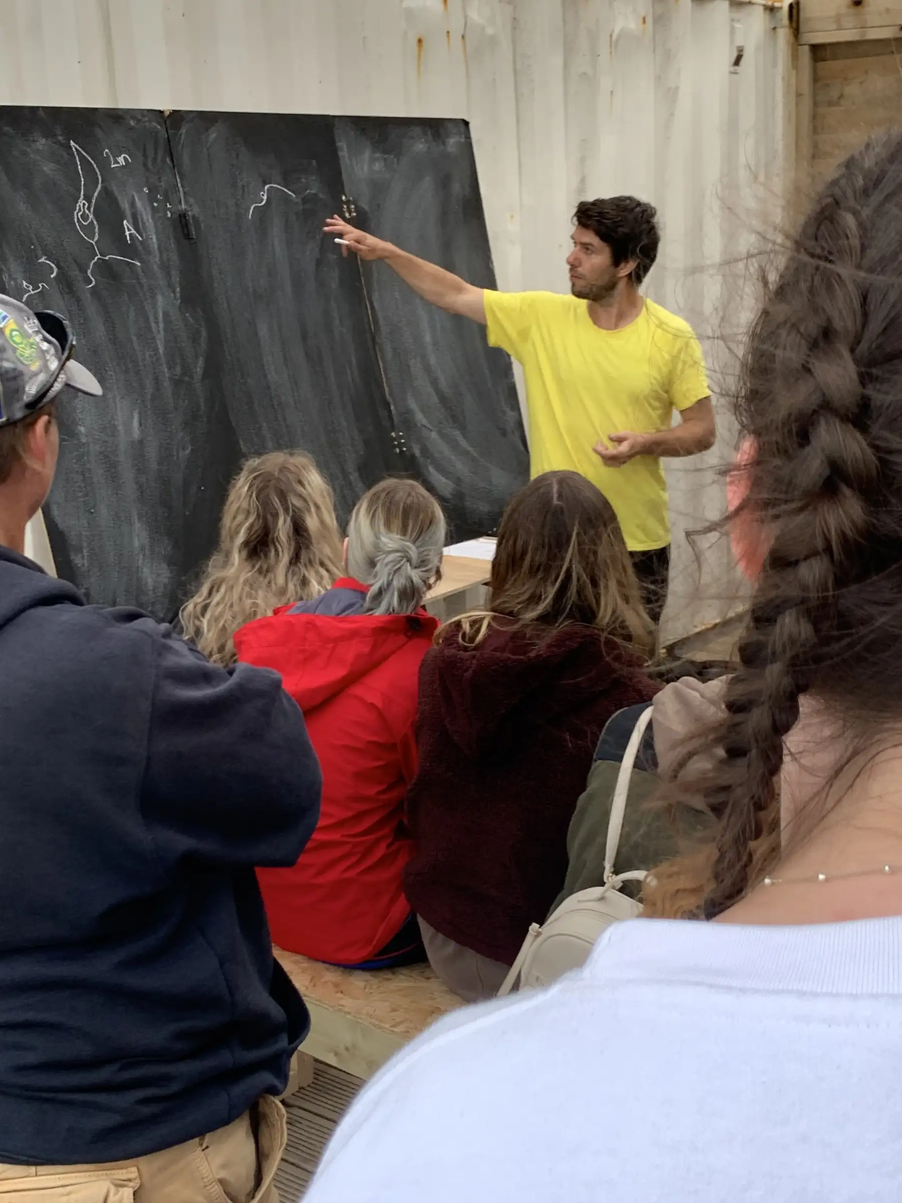 A talk on seaweed cultivation in front of a blackboard
